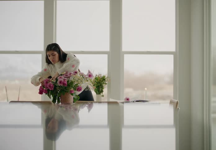 Florist arranges flowers in front of a wall of windows