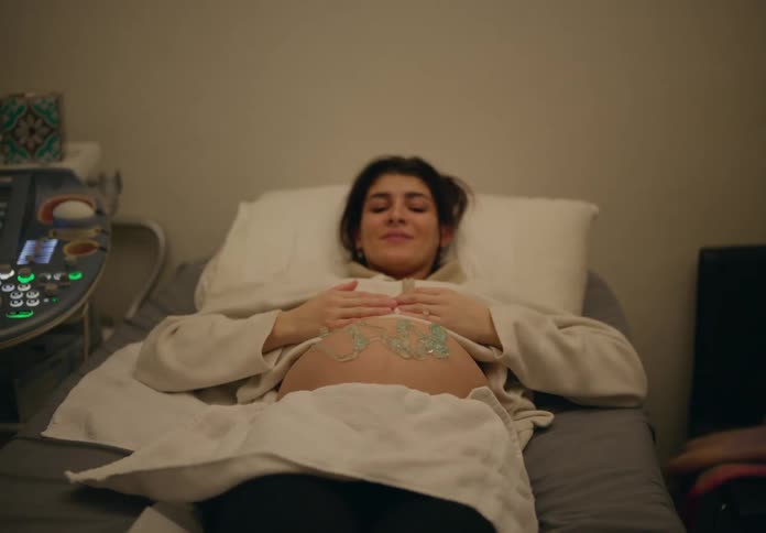 A woman lying on a medical examination bed with her abdomen exposed undergoing an ultrasound procedure