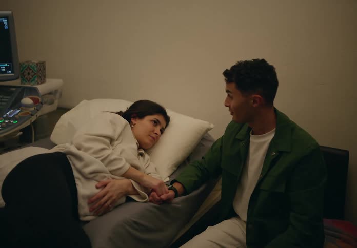 Woman lying on a hospital gurney pregnant next to a man
