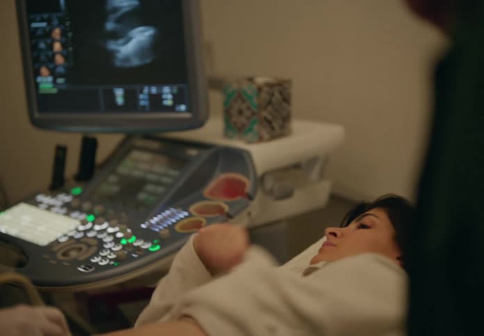 Pregnant woman lying down with her husband next to her doing an ultrasound