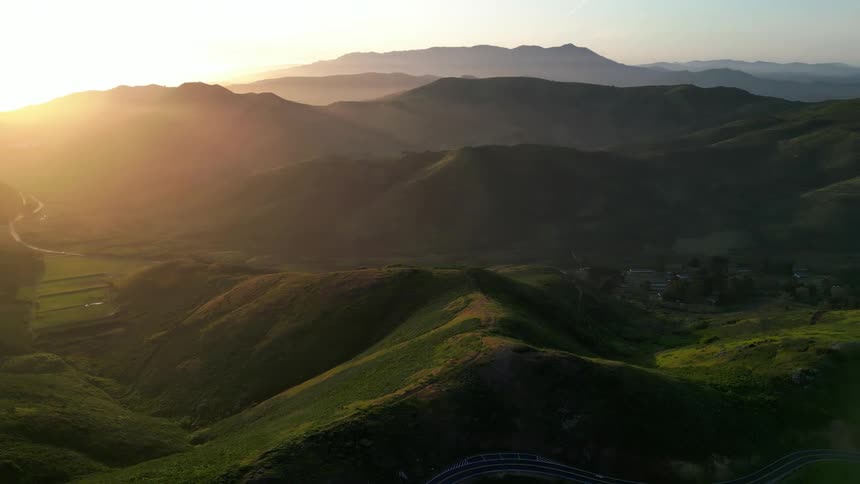 Village nestled in the grassy mountains at sunrise