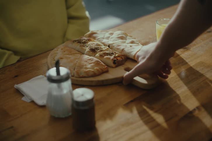 Server serves wooden board with three different savory pastry dishes to customer