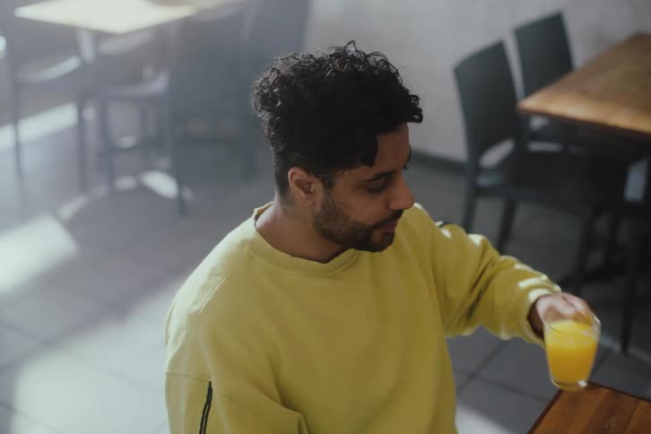 Man sitting at a restaurant table drinking a juice