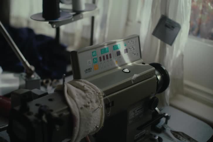 A closeup of a control panel over a sewing machine near a window with daylight