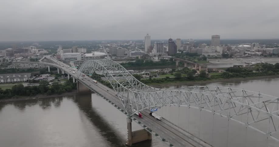 Aerial panorama of a bridge over the sea with a metropolis in the background on a cloudy day