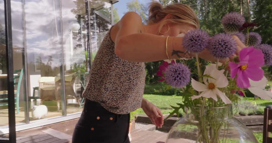 Woman making a flower arrangement in a clear vase