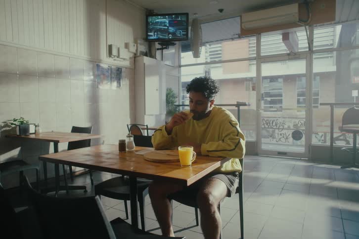 Man sitting at a restaurant table eating a sandwich
