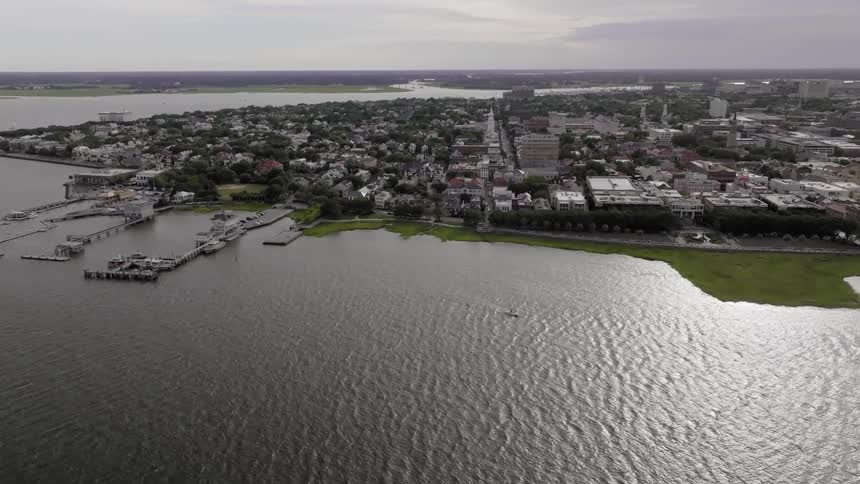 An aerial view of a city facing a large body of water with a few piers
