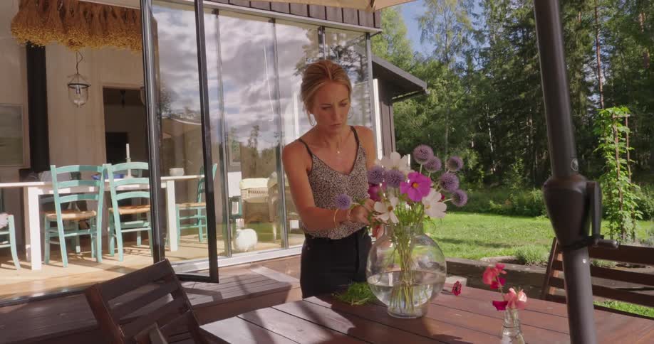 Woman pointing at a flower vase on a table with an umbrella