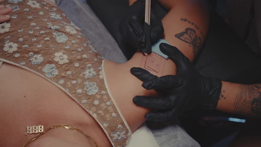 Tattoo artist adds a tattoo to the arm of a client