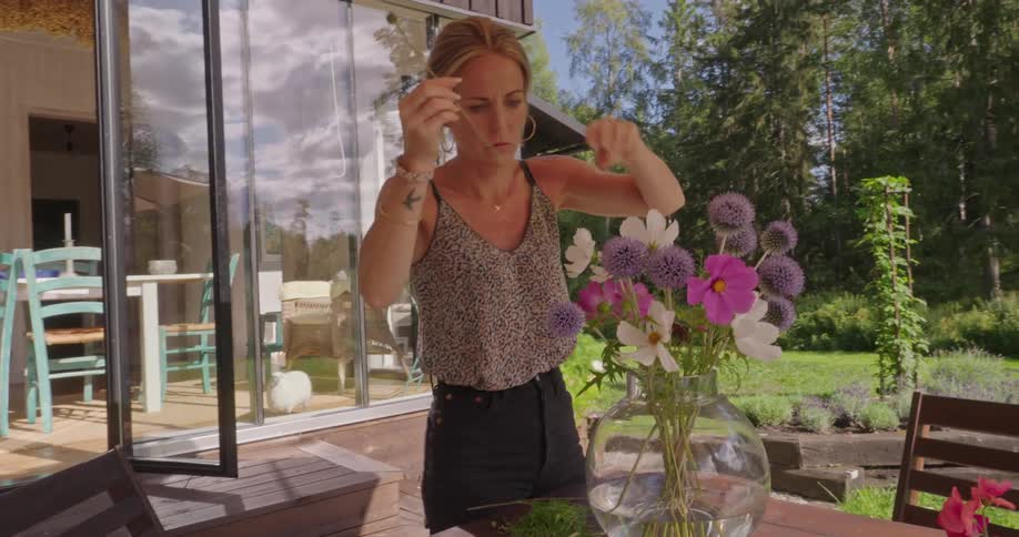 A woman is arranging flowers in a vase
