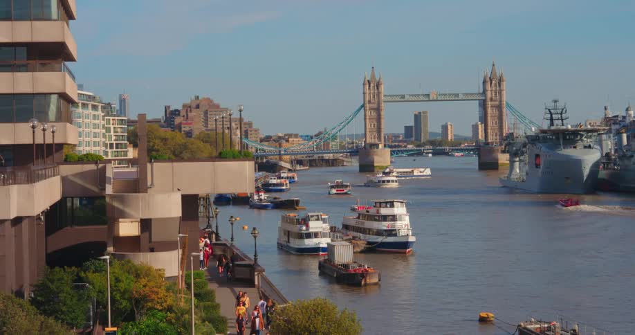 Some boats are in the water on a body of water next to a large city with a large bridge in the background