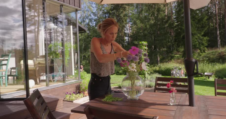 A woman is arranging flowers in a vase
