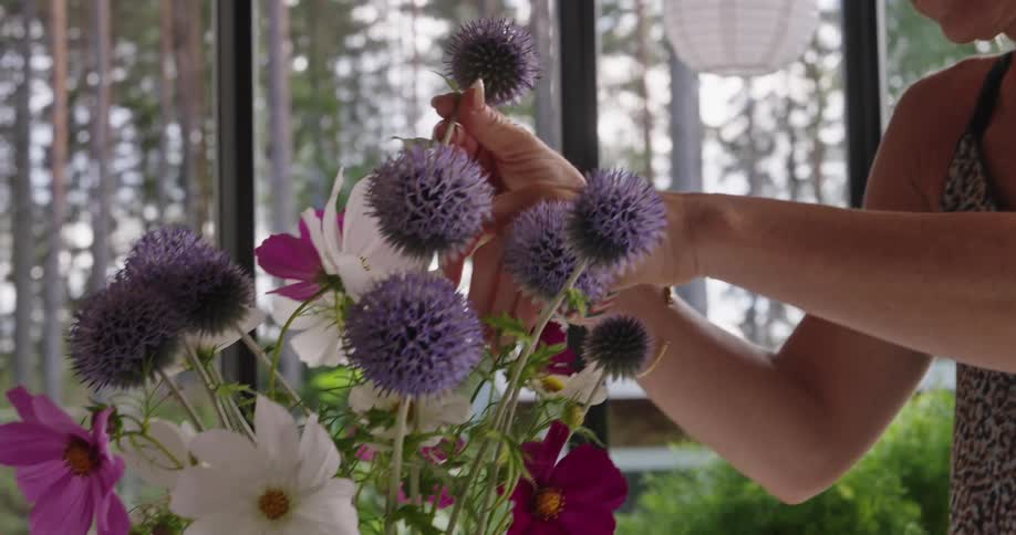 A woman making a flower arrangement in a glass vase