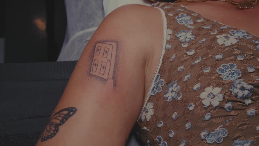 The arm of a woman who is lying down and he has a tattoo of a black door