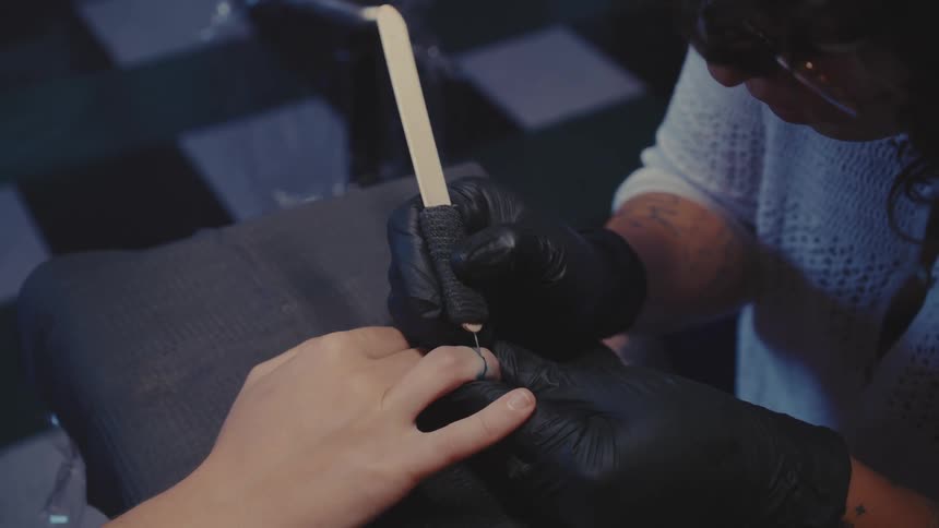 Concentrated woman tattooing a clients fingers