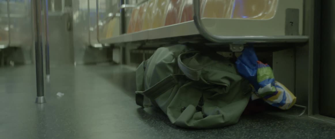 A camping bag under a train seating bench