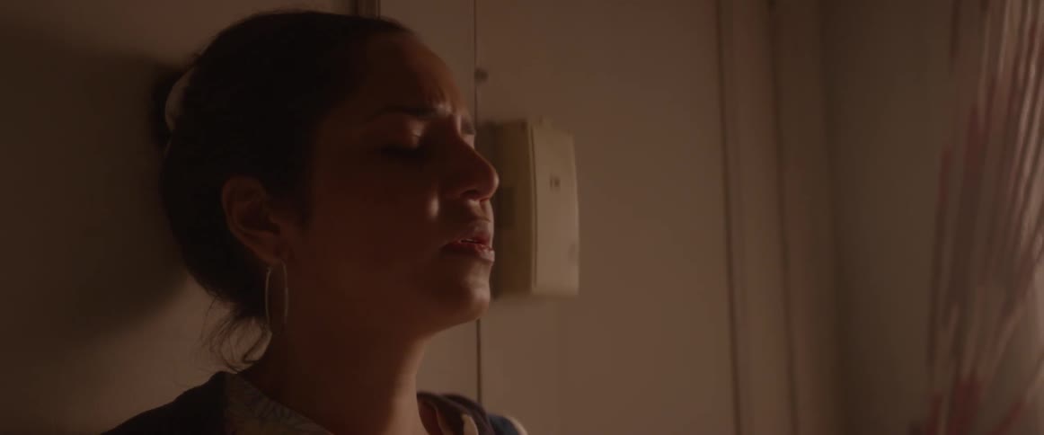 A woman leans against a door while looking concerned
