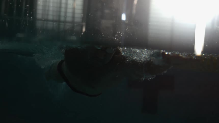 A person swimming crawl in a pool using their arms and lifting a lot of water