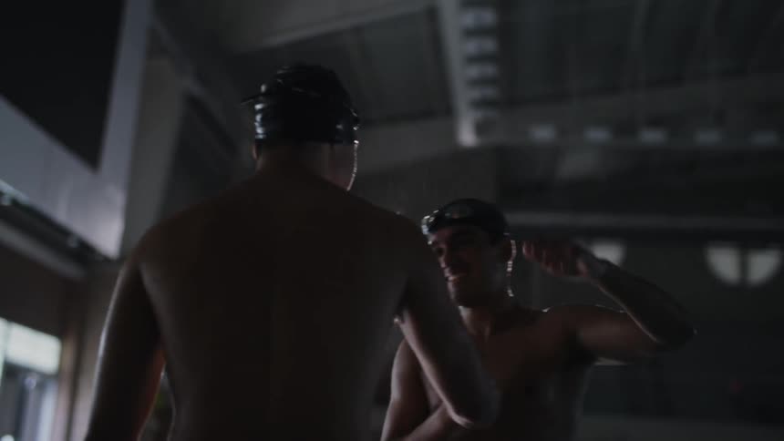 Two boys with swimming caps greeting and hugging each other