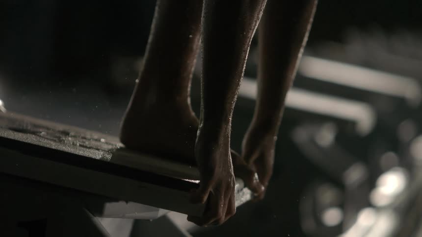 Person focused and waiting at the starting point of a swimming pool