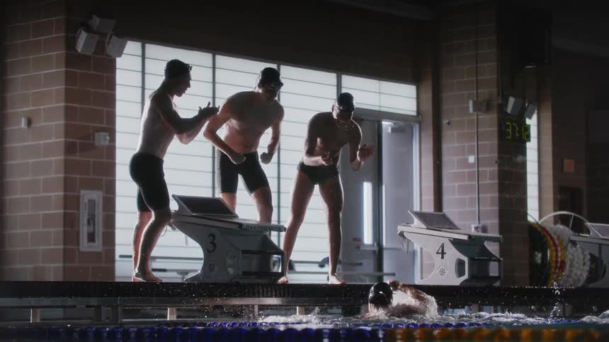 A group of swimmers celebrate as a teammate finishes a lap in the swimming pool