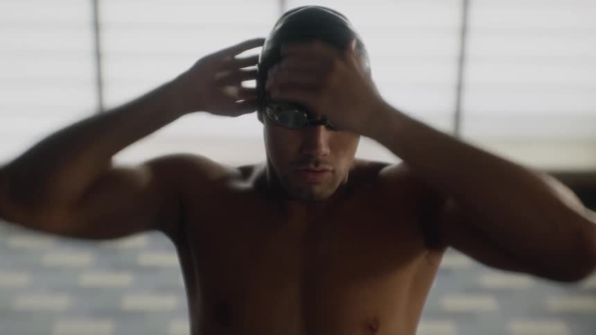 A swimmer wearing goggles and a cap prepares to swim