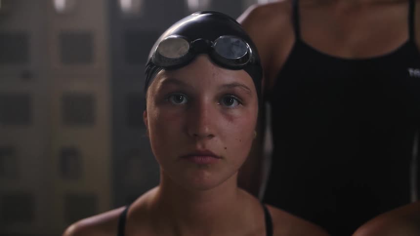 Close up of the face of a young swimmer wearing a cap and goggles