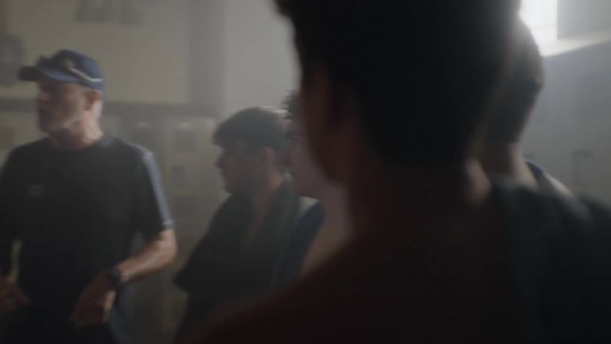 Team of teenagers paying attention to the coach inside a locker room and joining hands