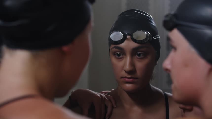 Group of female swimmers talking to each other in a locker room