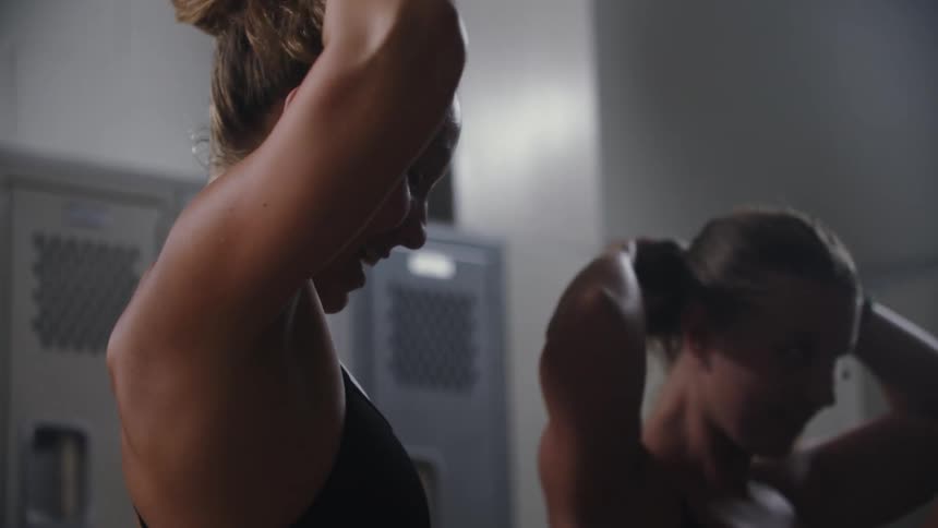 Team of female swimmers tie up their hair while in the locker room
