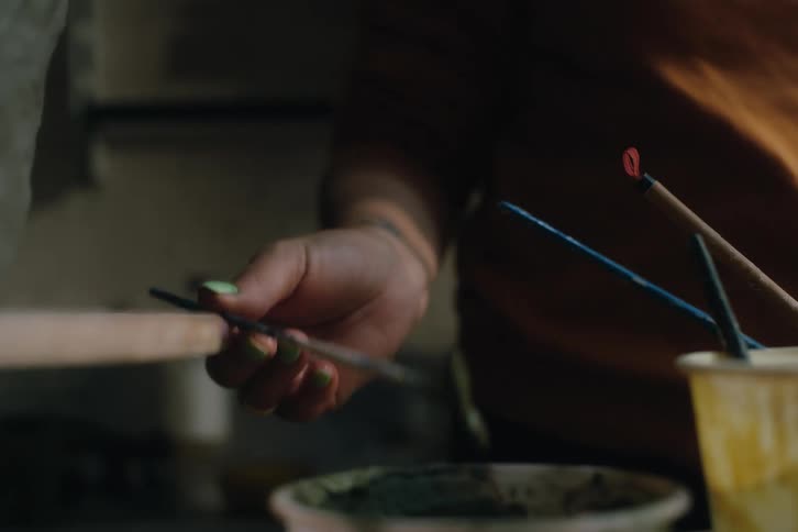 Person picking up a tool with paint on it
