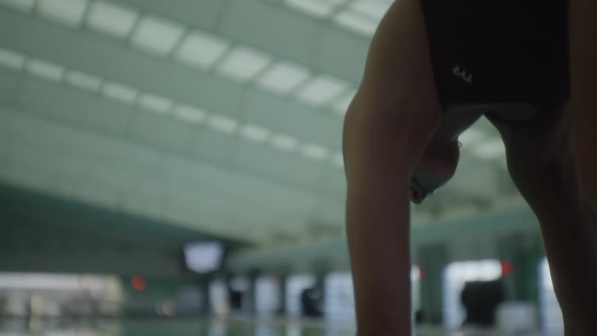 Young woman preparing and positioned jumping into the lane of a swimming pool