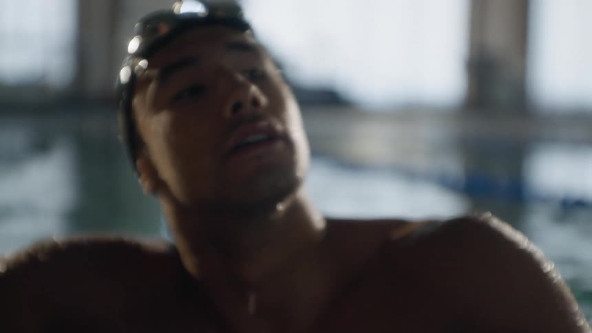 A man removes his goggles in the pool