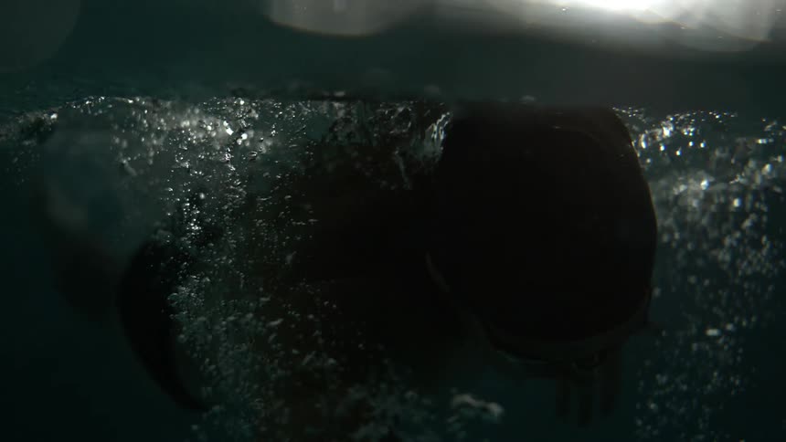A swimmer in a dimly lit pool setting during a swim practice
