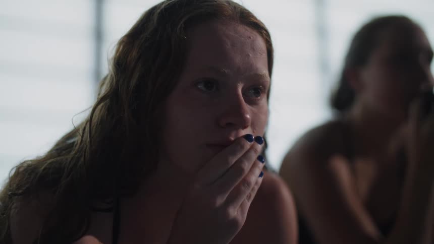Closeup of a womans face wearing a swimsuit with a hand over her mouth