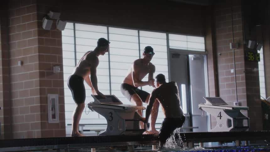 Two friends helping a colleague out of the pool and greeting each other by clapping and hugging