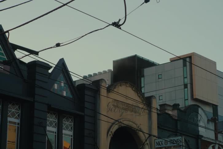 Some black buildings with several windows and several light wires in the front