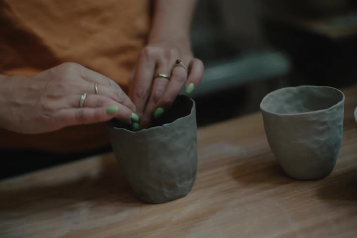 A human hand shaping a handmade ceramic cup