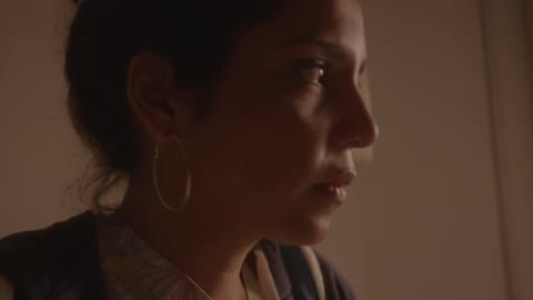 A woman with dark hair swallows and looks up before walking away