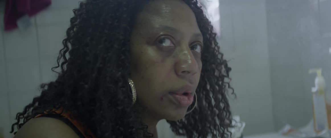 A woman blows smoke and looks to the side