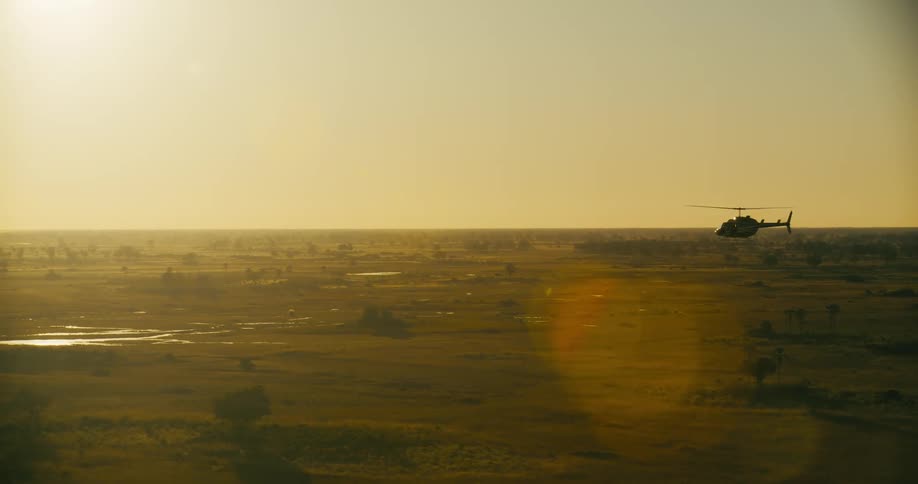 A helicopter flying over a savanna