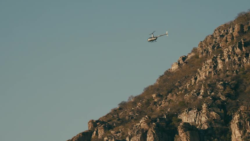 A helicopter flying over a rocky mountain