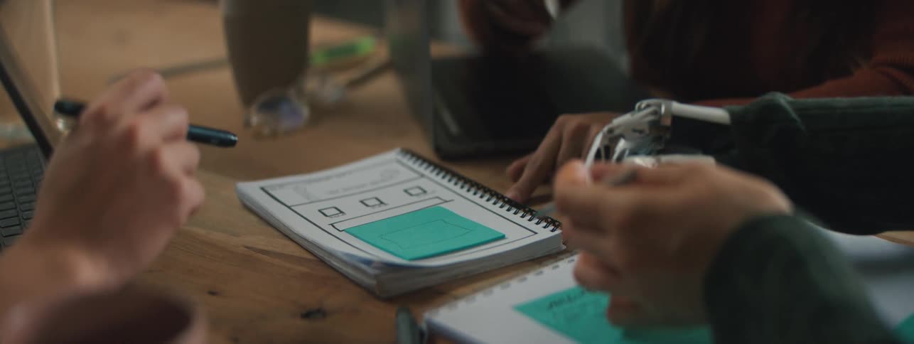 A group of people sitting at a table writing notes one of them with a prosthetic arm