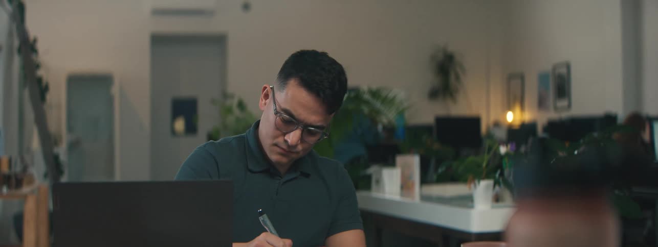 Man in an office sitting writing with a pen