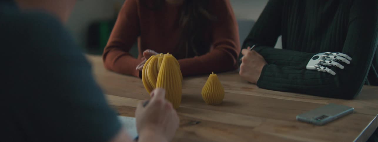 Group of three people sitting at a table with abstract objects on the table