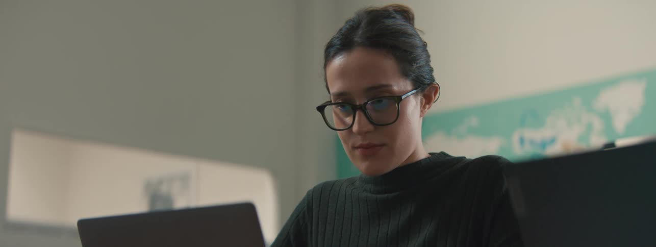 Woman in front of a laptop putting on her prescription glasses