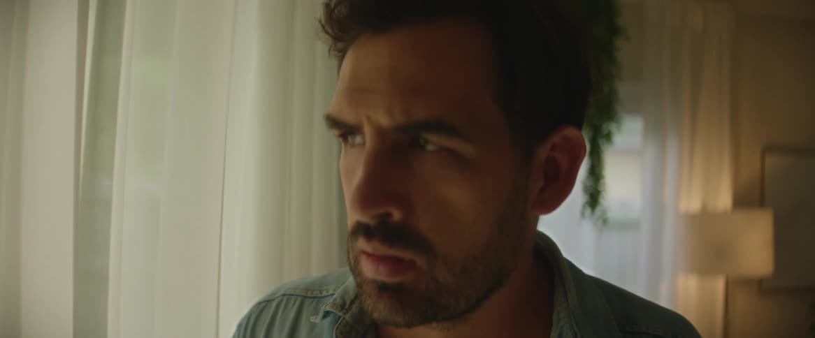 A man receiving bad news on his phone and looking contemplatively out the window.