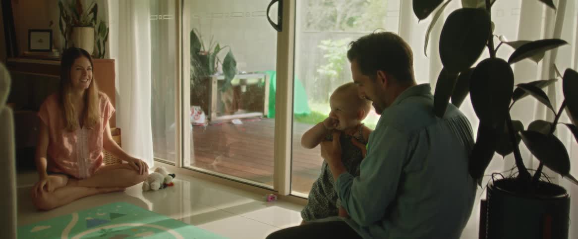Couple teach their baby to take his first steps at home