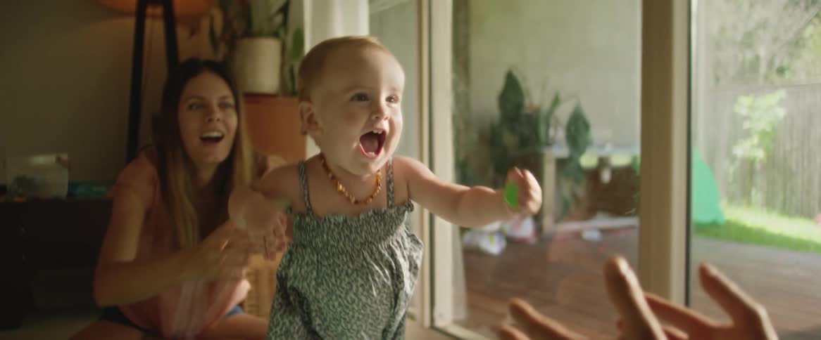 Parents smile as daughter toddles from one of them to the other